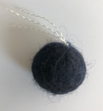 closeup of wool ball with thread "tail" are small enough for a cat to pick up with their mouth to carry or toss, just over an inch (2.5 cm) in diameter